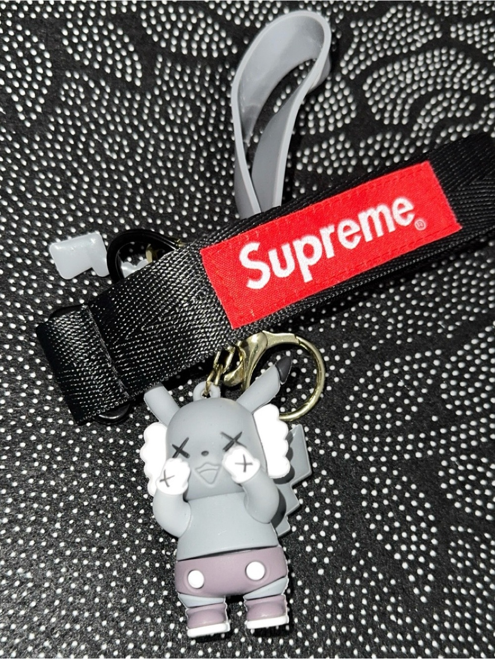 Supreme black and red lanyard with gray KAWS-style keychain